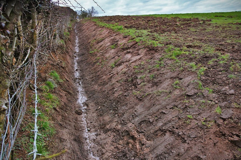 Over time drain may become blocked with silt / grass. Cleaning drains in fields for reseeding will improve their performance.