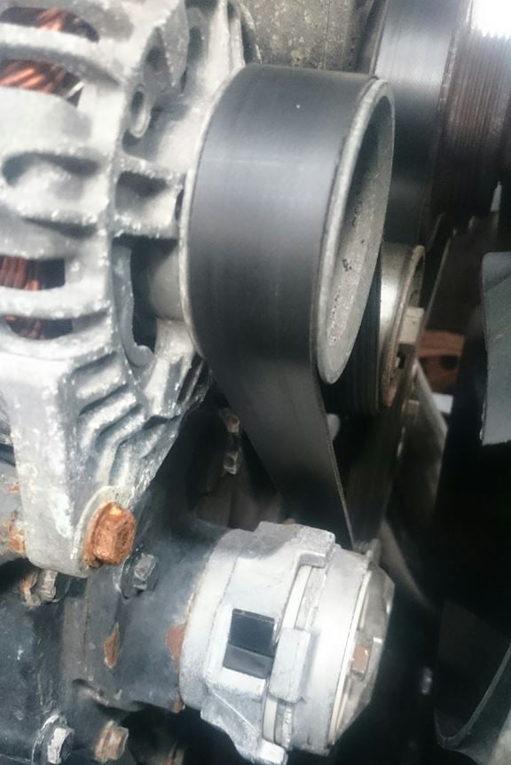 The tensioner and alternator on a tractor engine