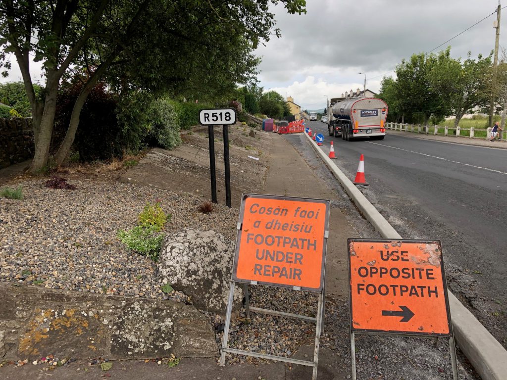 The works being carried out on the footpath means that the traffic entering the village from the north side is forced to travel over the white line