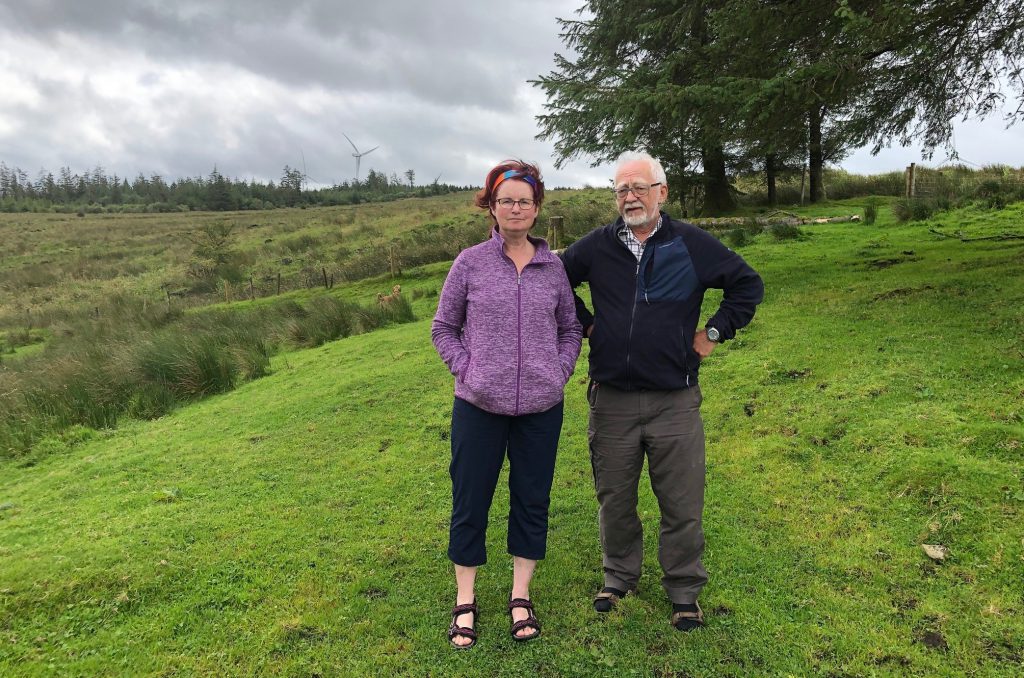 Adrienne Diamond and Graham Robertson at their home in Killavoggy – wind turbines that are part of a private development are clearly visible behind them