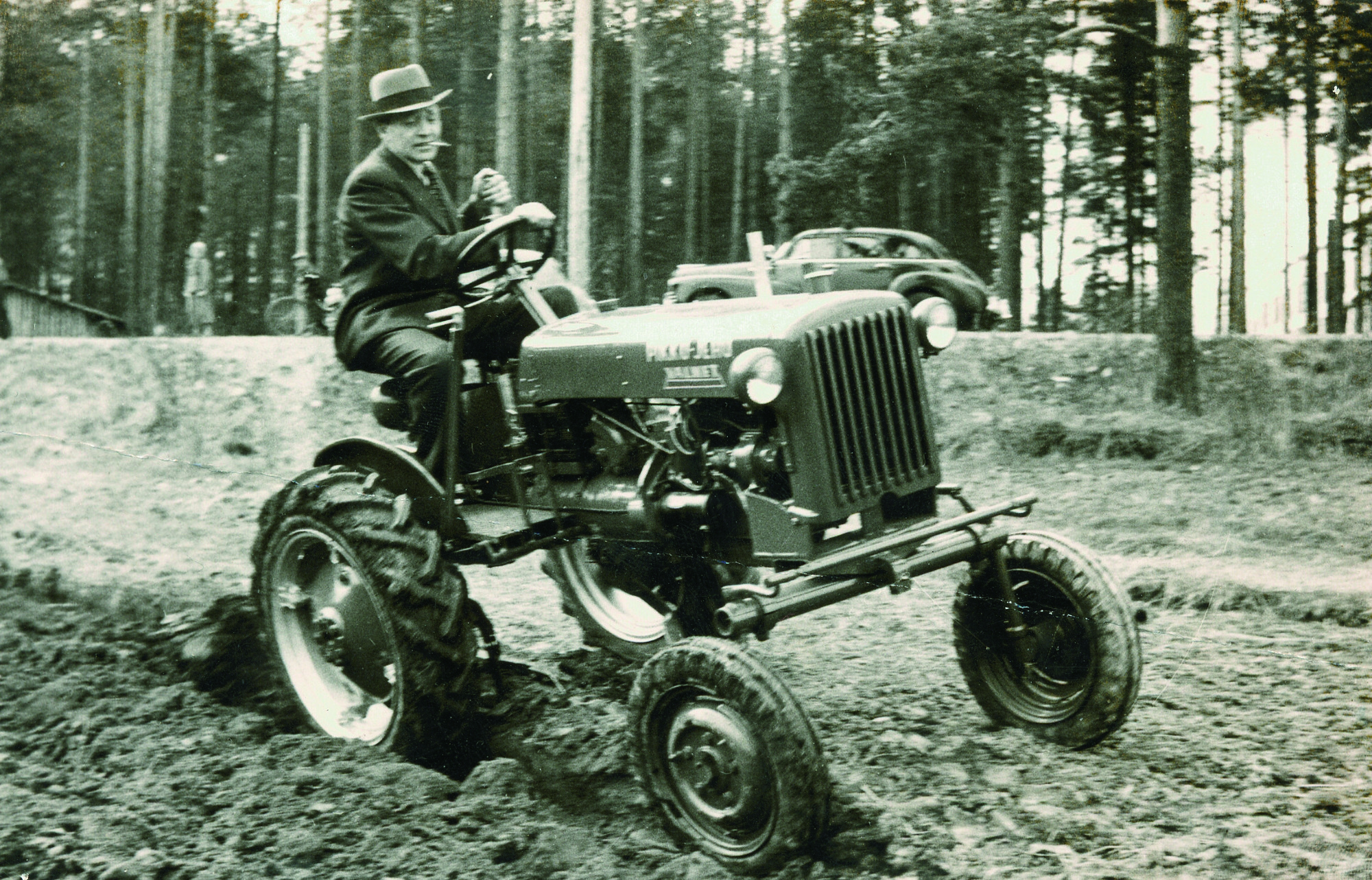 Valmet 's first chief engineer, Olavi Sipila, drives a Model A at a ploughing demonstration in suit and tie