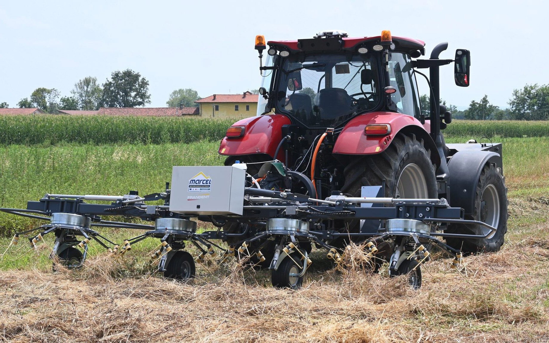 The four-rotor tedder appears to be driven by a front-mounted generator