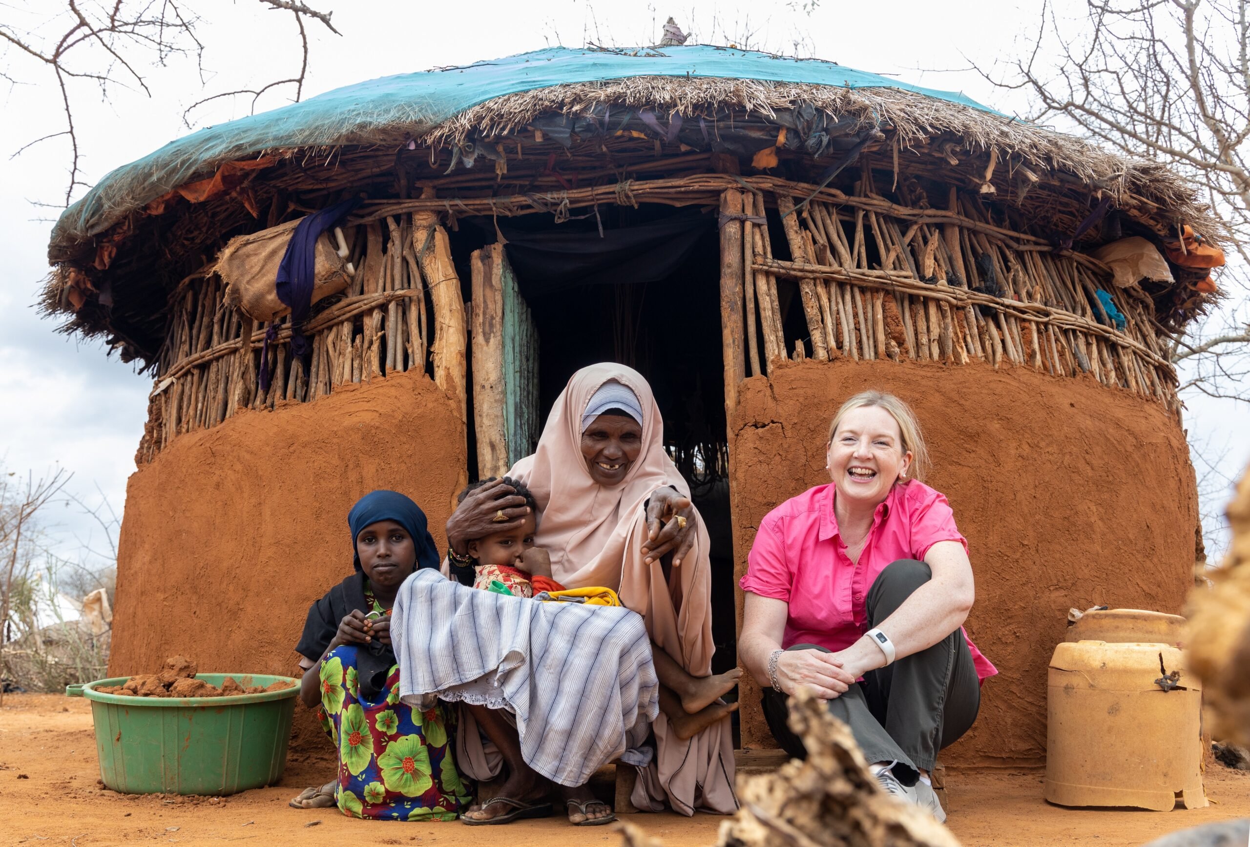 Rosamond sits outside the home of 65-year-old farmer Fatuma Said Kassim from the village of Qoloba alongside her grandchildren.Image source: Norah Rotich
