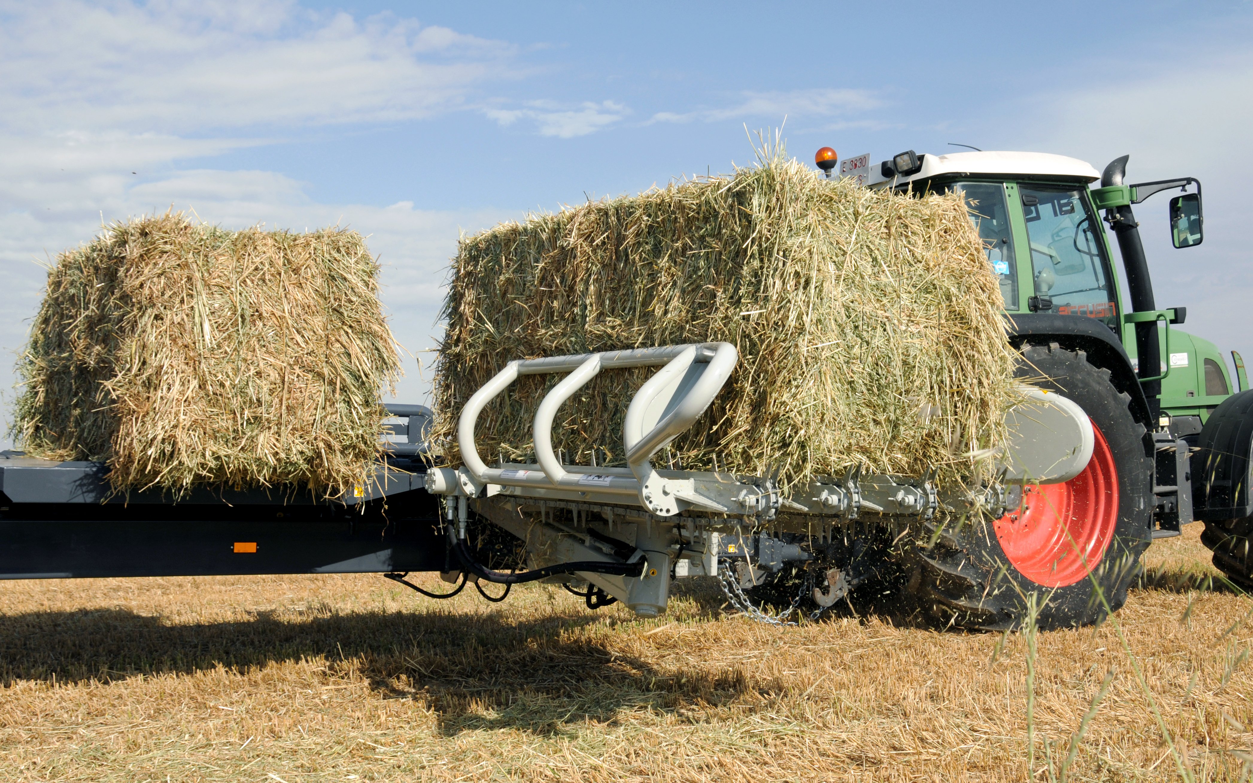 Large square bales are collected and turned before being accumulated in two tiers on the trailer