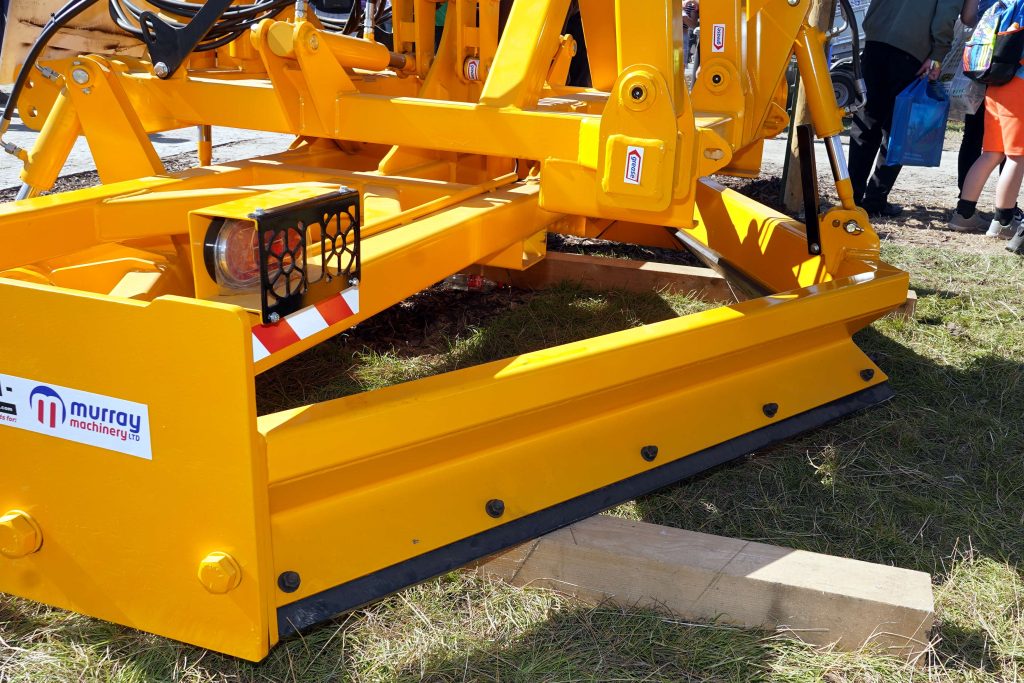 The rear levelling blades draw the loos material back into the centre as it smooths the roadway surface