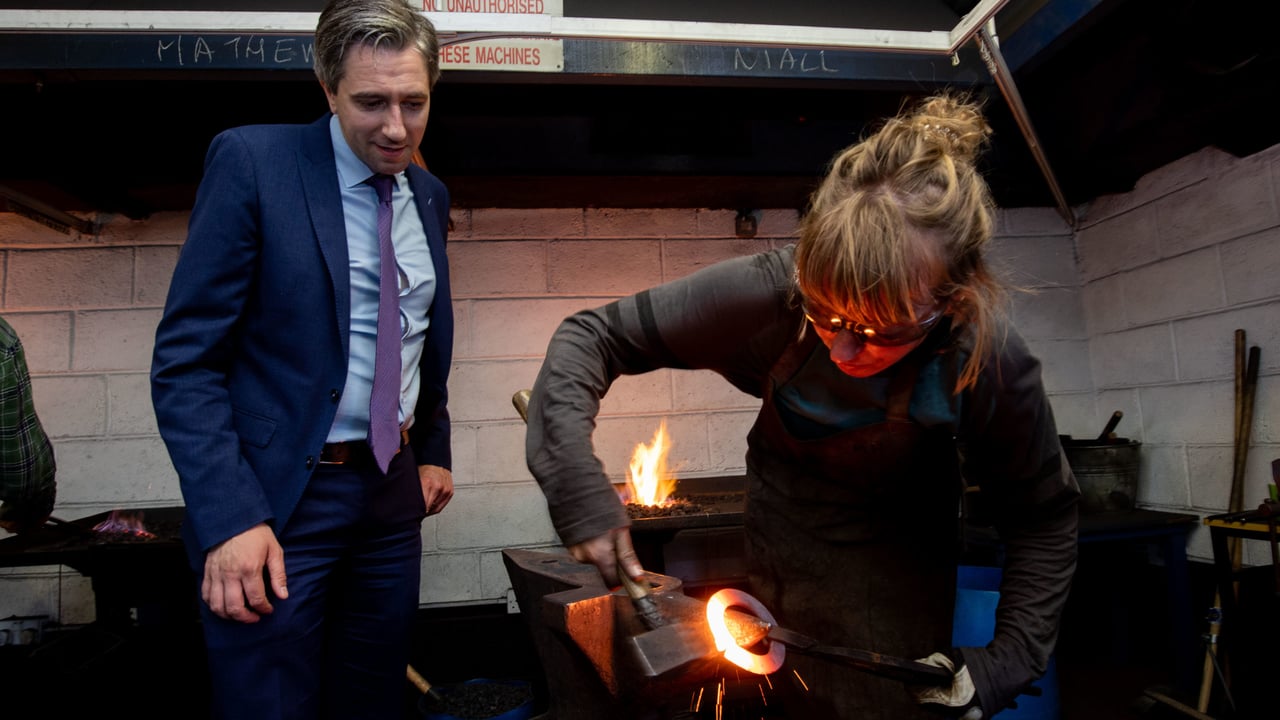 Minister for further and higher education, research, innovation and science, Simon Harris watches trainee blacksmith Mary Hallinan at work in the blacksmithing forge. Image source: Alan Place