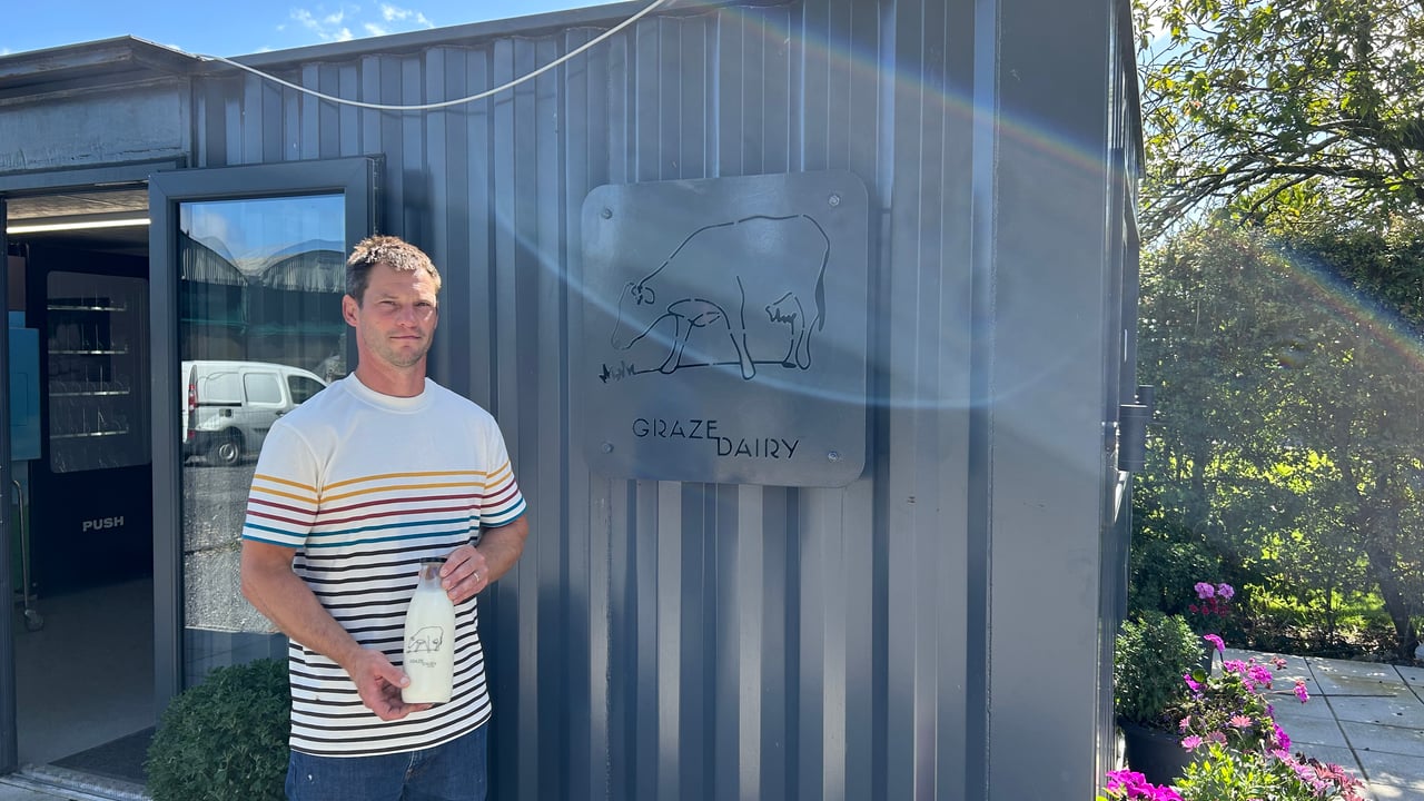 Mark Gray with a bottle of milk outside Graze Dairy shop 