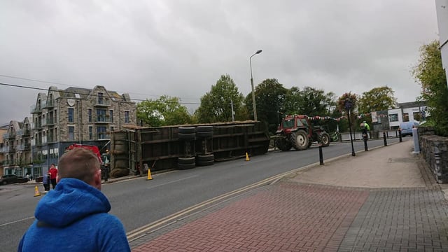 Trailer carrying bales overturns on bridge